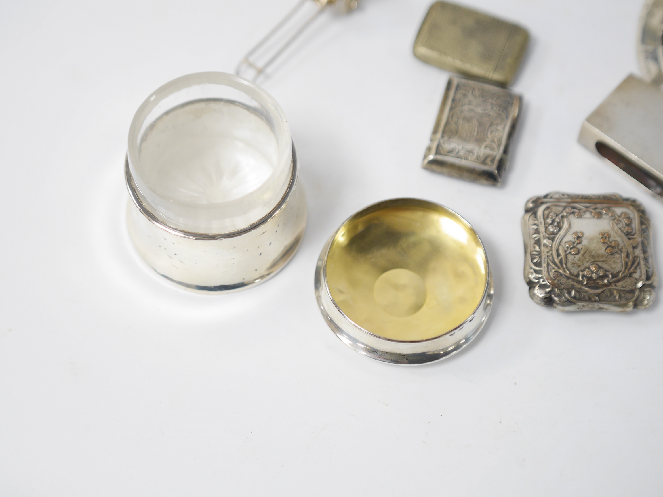 Assorted small collectables including a late Victorian silver vesta case, Birmingham, 1898, a small silver mounted circular photograph frame, a silver mounted glass pot and cover, a silver matchbox sleeve and three other